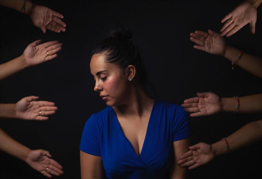 woman with arms reaching to her in the dark