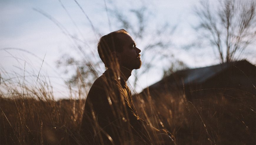 man in field meditating